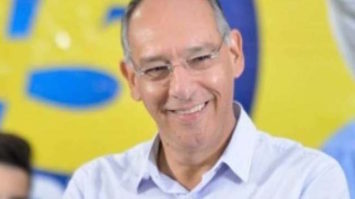 #pracegover: foto em close do prefeito Hélio Peluffo de óculos e sorrindo, vestindo camisa azul clara