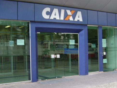 #pracegover: foto mostra fachada de uma agência da Caixa Econômica Federal em azul com o nome do banco em destaque CAIXA