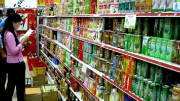 #pracegover: foto mostra mulher olhando lista de compras em corredor de supermercado