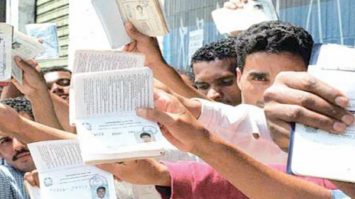 #pracegover: foto mostra pessoas segurando a carteira de trabalho aberta em fila