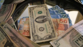 #pracegover: foto mostra notas dólar sob notas de R$ 100 e R$ 50