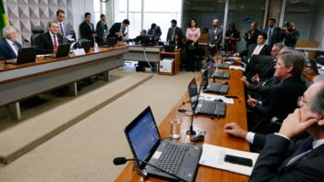 #pracegover: Ataídes de Oliveira está sentado na Comissão de Transparência no Senado com outros parlamentares. Em frente a ele, bancada com outros senadores