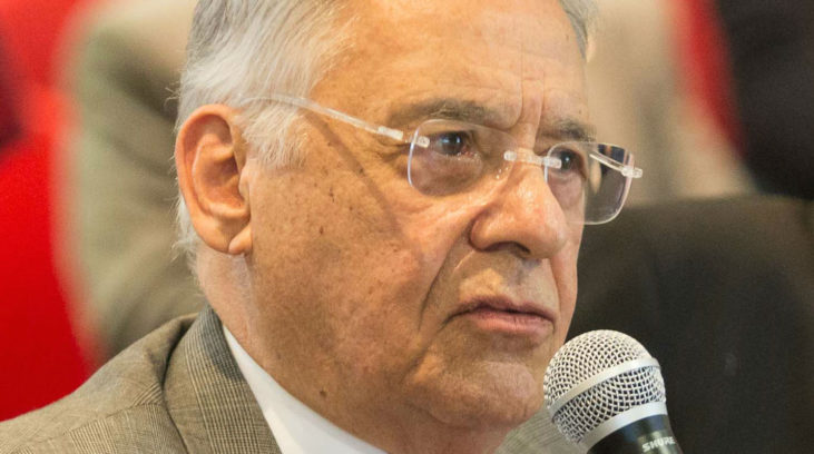 #pracegover: foto de perfil do ex-presidente FHC segurando microfone e vestindo paletó marrom, blusa branca, óculos e gravata