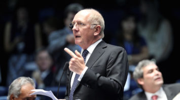 #pracegover: foto mostra o senador Paulo Bauer em pé, falando ao microfone. Ele gesticula a mão esquerda com dedo indicador apontado e na outra, segura papeis
