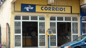 #pracegover: foto mostra fachada de agência dos Correios e um carro estacionado na frente