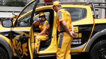 #pracegover: foto mostra veículo novo amarelo e preto com uma agente de transito sentada e outro em pé de costas
